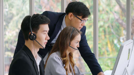 Business people wearing headset working in office to support remote customer or colleague. Call center, telemarketing, customer support agent provide service on telephone video conference call.の写真素材