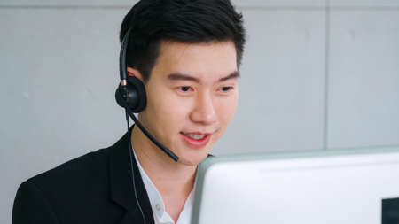 Business people wearing headset working in office to support remote customer or colleague. Call center, telemarketing, customer support agent provide service on telephone video conference call.の写真素材