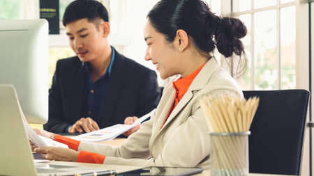 Two business people talk project strategy at office meeting room. Businessman discuss project planning with colleague at modern workplace while having conversation and advice on financial data report.の写真素材