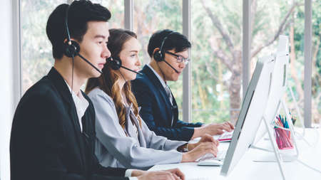 Business people wearing headset working in office to support remote customer or colleague. Call center, telemarketing, customer support agent provide service on telephone video conference call.の写真素材