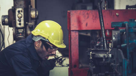 Factory worker talking on portable radio while inspecting machinery parts . Industrial and engineering team communication concept .の写真素材