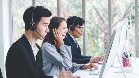 Business people wearing headset working in office to support remote customer or colleague. Call center, telemarketing, customer support agent provide service on telephone video conference call.の写真素材