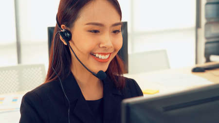 Business people wearing headset working in office to support remote customer or colleague. Call center, telemarketing, customer support agent provide service on telephone video conference call.の写真素材