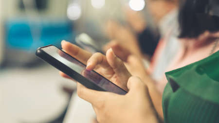 Young people using mobile phone in public underground train . Urban city lifestyle and commuting in Asia concept .の写真素材