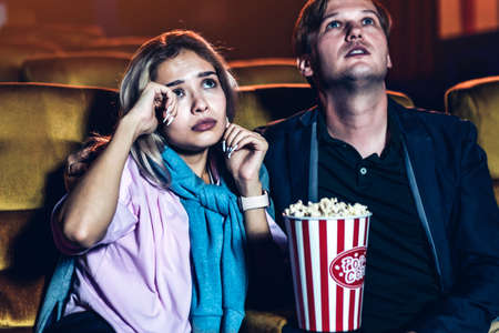 Caucasian man and woman watching a sad movie and his girlfriend cryingの写真素材