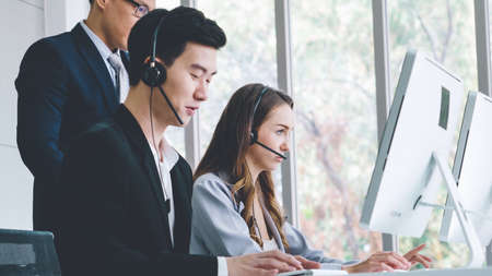 Business people wearing headset working in office to support remote customer or colleague. Call center, telemarketing, customer support agent provide service on telephone video conference call.の写真素材