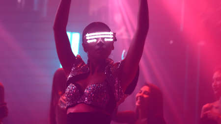 Group of people dance in disco night club to the beat of music from DJ on stage . New year night party and nightlife concept .の写真素材