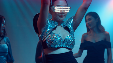 Group of people dance in disco night club to the beat of music from DJ on stage . New year night party and nightlife concept .の写真素材