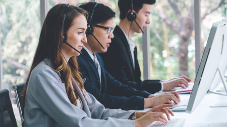 Business people wearing headset working in office to support remote customer or colleague. Call center, telemarketing, customer support agent provide service on telephone video conference call.の写真素材