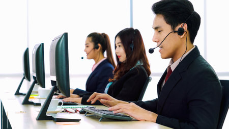 Business people wearing headset working in office to support remote customer or colleague. Call center, telemarketing, customer support agent provide service on telephone video conference call.の写真素材