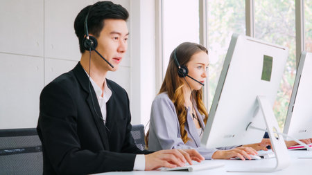 Business people wearing headset working in office to support remote customer or colleague. Call center, telemarketing, customer support agent provide service on telephone video conference call.の写真素材