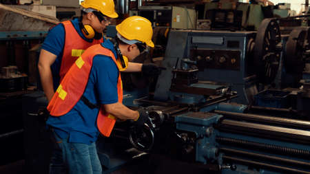 Group of skillful factory workers using machine equipment in workshop . Industry and engineering people technology concept .の写真素材