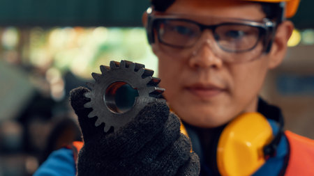 Skillful factory worker looking at machine part in workshop . Industry and engineering technology...