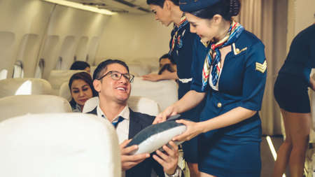 Cabin crew give service to passenger in airplane . Airline transportation and tourism concept.の写真素材