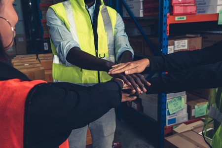 Factory workers stacking hands together in warehouse or storehouse . Logistics , supply chain and...