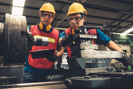 Group of skillful factory workers using machine equipment in workshop . Industry and engineering people technology concept .の写真素材