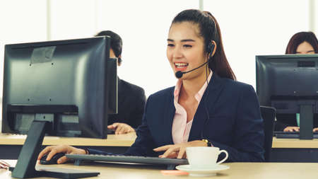 Business people wearing headset working in office to support remote customer or colleague. Call center, telemarketing, customer support agent provide service on telephone video conference call.の写真素材