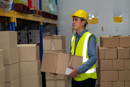 Asian warehouse worker checking packages in storehouse . Logistics , supply chain and warehouse business concept .の写真素材