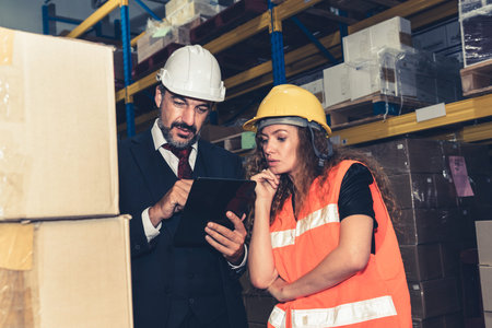 Warehouse senior manager discuss with worker in the storehouse . Logistics , supply chain and...