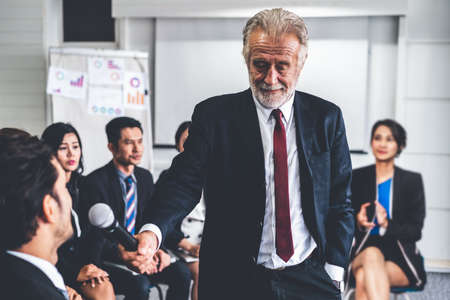 Senior leader speaker speaks to public people audience in training workshop or conference. Mature lecturer is CEO executive manager leading the symposium event. International business seminar concept.の写真素材