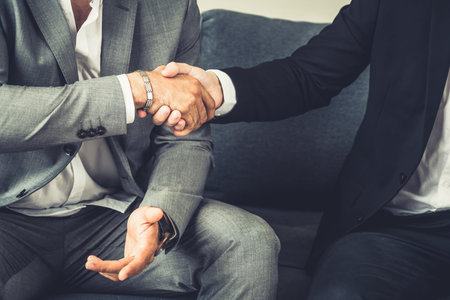 Businessman handshake with another businessman partner in modern workplace office. People corporate...