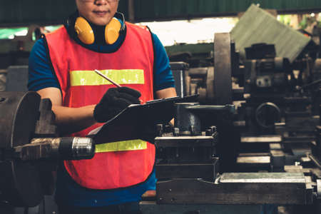 Skillful factory worker working with clipboard to do job procedure checklistの写真素材