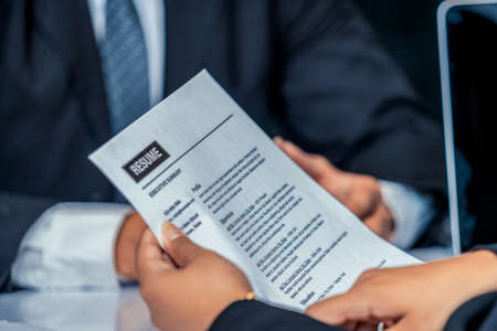 Human resources department manager reads CV resume document of an employee candidate at interview room.の写真素材