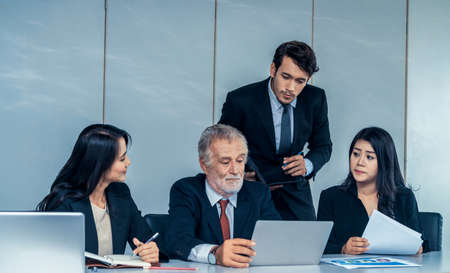 Senior caucasian manager working in office with assistance of young Asian business people and translator in the meeting. Corporate international business and secretary language translation concept.の写真素材