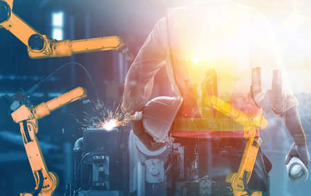 Mechanized industry robot arm and factory worker double exposure . Concept of robotics technology for industrial revolution and automated manufacturing process .の写真素材
