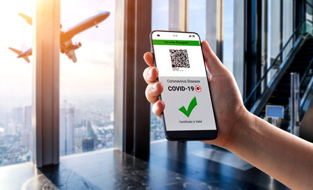 Traveler holds vaccine passport certificate to show COVID 19 vaccination status . The digital health...