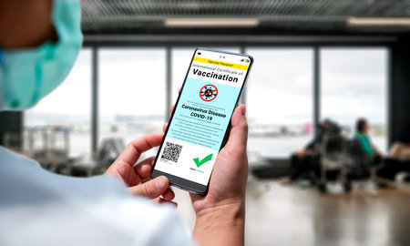 Traveler holds vaccine passport certificate to show COVID 19 vaccination status . The digital health...