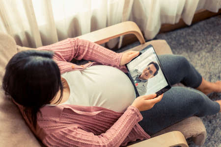 Doctor telemedicine service online video with pregnant woman for prenatal care . Remote doctor healthcare consultant from home using online mobile device connect to internet for live video call .の写真素材