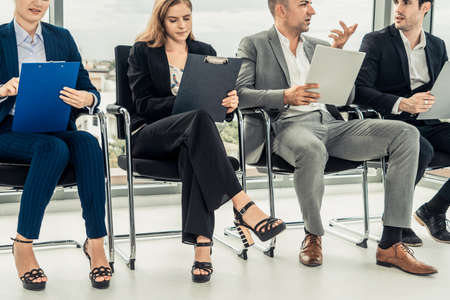 Businesswomen and businessmen holding resume CV folder while waiting on chairs in office for job interview. Corporate business and human resources concept.の写真素材