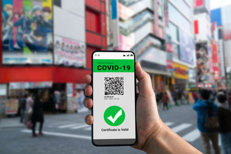 Traveler holds vaccine passport certificate to show COVID 19 vaccination status . The digital health certificate is required for international travel during coronavirus pandemic .の写真素材
