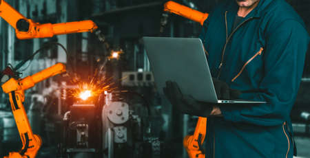 Engineer use advanced robotic software to control industry robot arm in factory . Automation manufacturing process controlled by specialist using IOT software connected to internet network .の写真素材