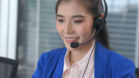 Businesswoman wearing headset working actively in office . Call center, telemarketing, customer support agent provide service on telephone video conference call.の写真素材