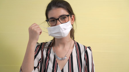Young woman take off face mask removing from face showing concept of the end of quarantine and...