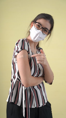 Young woman showing COVID-19 vaccine bandage merrily in concept of coronavirus vaccination program...