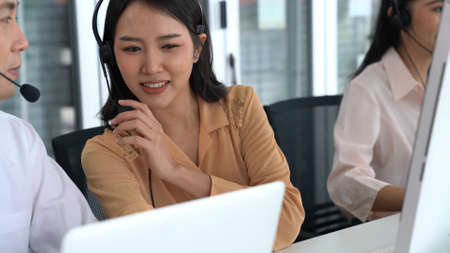 Business people wearing headset working actively in office . Call center, telemarketing, customer support agent provide service on telephone video conference call.の写真素材