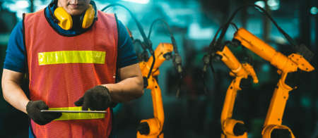 Engineer use advanced robotic software to control industry robot arm in factory . Automation manufacturing process controlled by specialist using IOT software connected to internet network .の写真素材