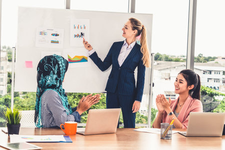 Multicultural working group. Team of businesswomen of different ethnicity, Caucasian, Asian and Arabic working together in team meeting with laptop computer at office. Multiethnic teamwork concept.の写真素材