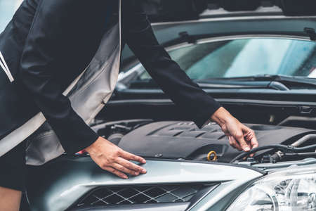 A business woman whose car breakdown try to fix the car by herself without help.の写真素材