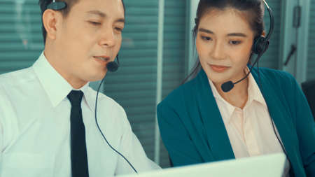 Business people wearing headset working actively in office . Call center, telemarketing, customer support agent provide service on telephone video conference call.の写真素材