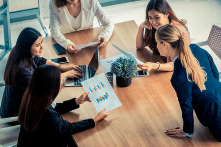 Businesswoman in group meeting discussion with other businesswomen colleagues in modern workplace office with laptop computer and documents on table. People corporate business working team concept.の写真素材