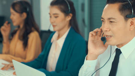 Business people wearing headset working actively in office . Call center, telemarketing, customer support agent provide service on telephone video conference call.の写真素材