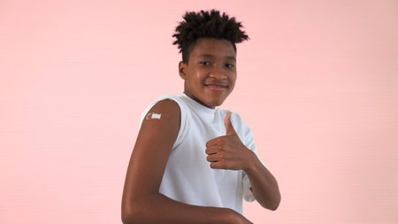 African American teenager showing vaccine bandage merrily in concept of virus vaccination program to vaccinate citizen .の写真素材