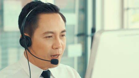 Businessman wearing headset working actively in office . Call center, telemarketing, customer support agent provide service on telephone video conference call.の写真素材