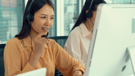 Businesswoman wearing headset working actively in office . Call center, telemarketing, customer support agent provide service on telephone video conference call.の写真素材