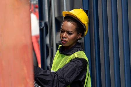Young African American woman worker at overseas shipping container yard . Logistics supply chain management and international goods export concept .の写真素材