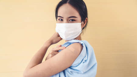 Young Asian woman showing COVID-19 vaccine bandage merrily in concept of coronavirus vaccination program to vaccinate citizen .の写真素材
